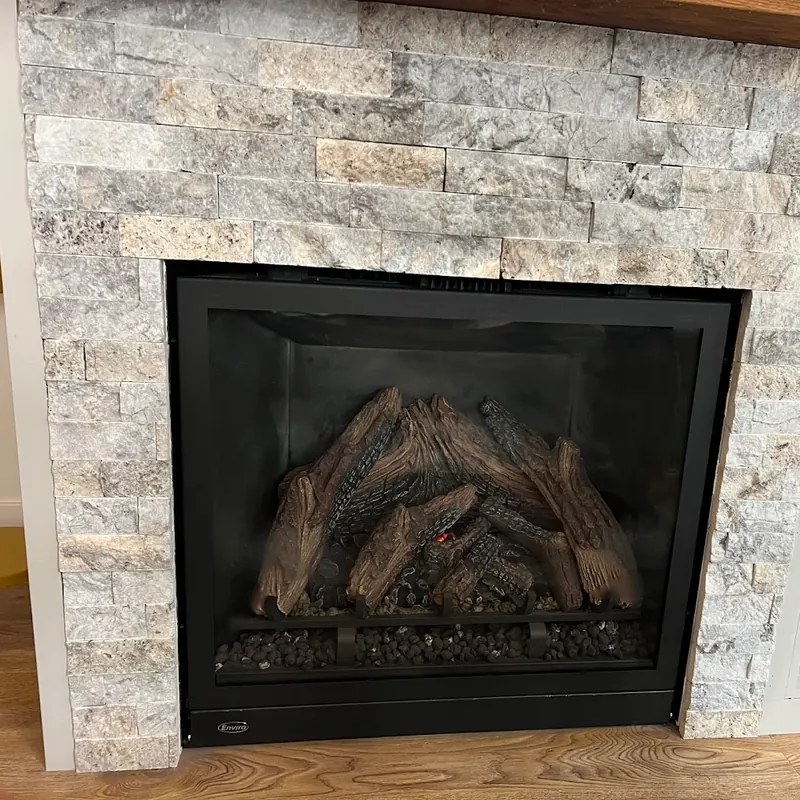 Enviro gas fireplace with a log set, framed in stacked stone