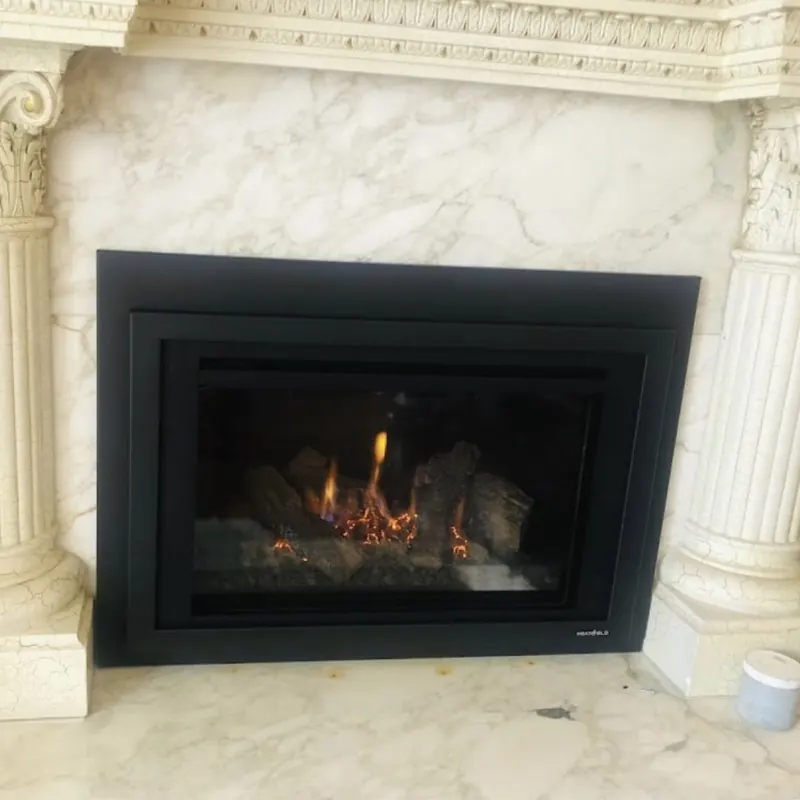 Black gas insert set into white marble between carved columns